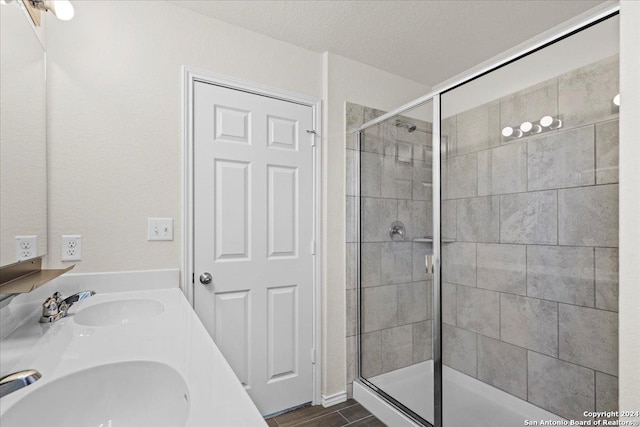 bathroom with a textured ceiling, vanity, and a shower with shower door