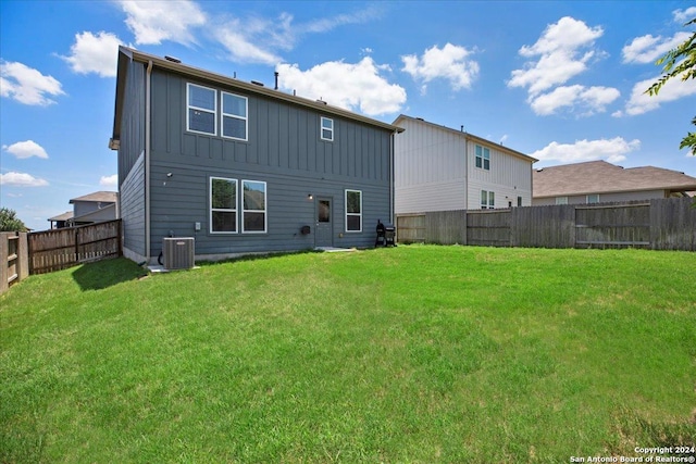 rear view of property featuring a lawn and central air condition unit