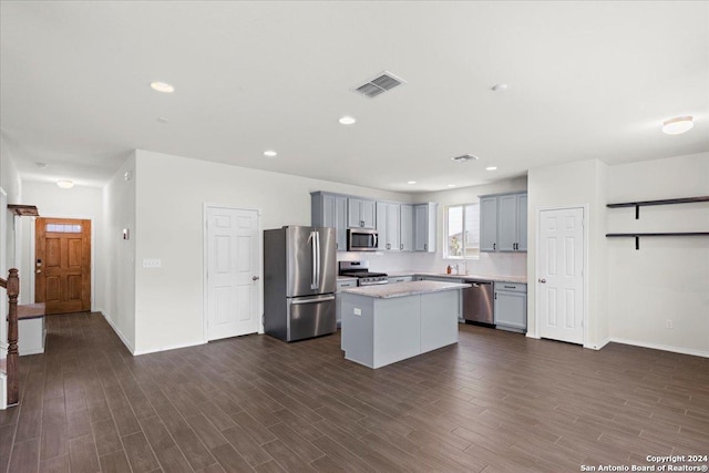 kitchen with gray cabinetry, a center island, tasteful backsplash, dark hardwood / wood-style floors, and appliances with stainless steel finishes