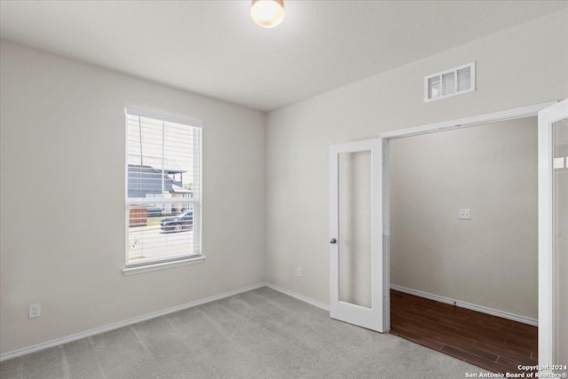 unfurnished bedroom with french doors, light colored carpet, and multiple windows