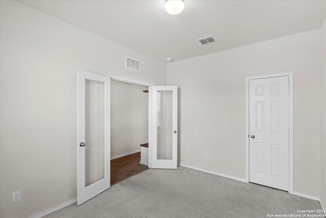 unfurnished bedroom featuring french doors and light colored carpet