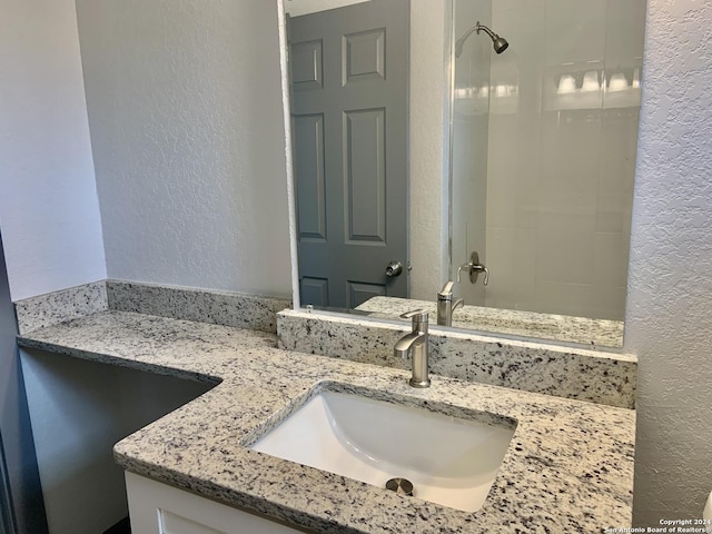 bathroom featuring a shower and vanity