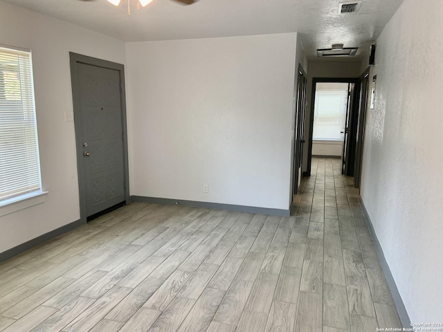 empty room featuring a textured ceiling, ceiling fan, and light hardwood / wood-style flooring