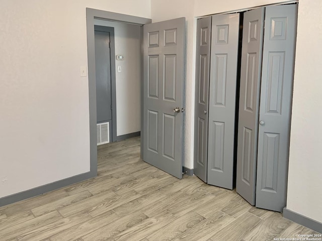 unfurnished bedroom with a closet and light hardwood / wood-style flooring