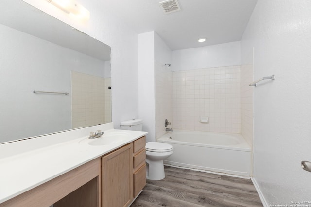 full bathroom featuring wood-type flooring, toilet, tiled shower / bath combo, and vanity