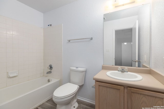 full bathroom featuring tiled shower / bath, vanity, and toilet