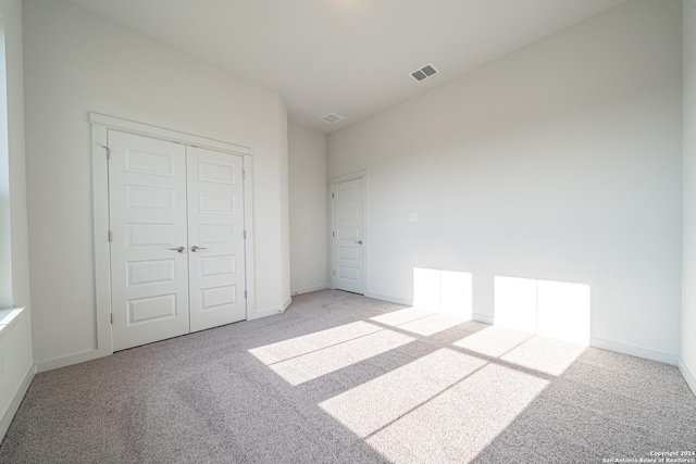 unfurnished bedroom with visible vents, light carpet, and a closet
