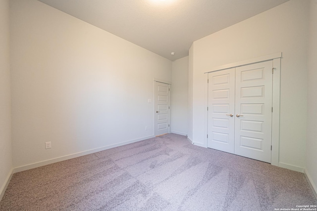 unfurnished bedroom with carpet flooring, vaulted ceiling, and baseboards