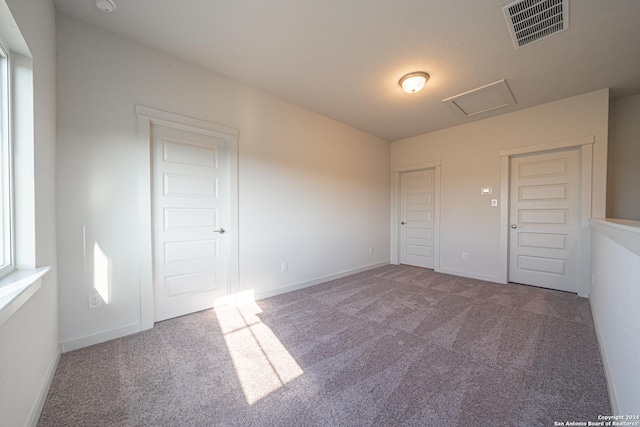 unfurnished bedroom featuring attic access, carpet, visible vents, and baseboards