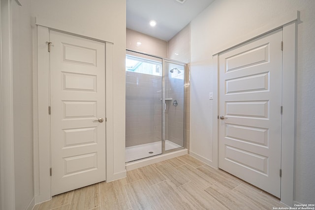 full bath with wood finished floors, a stall shower, and baseboards