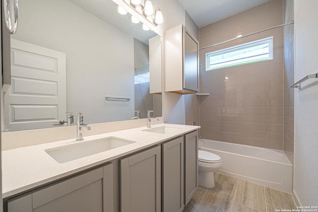 full bath featuring toilet, shower / bathtub combination, double vanity, and a sink