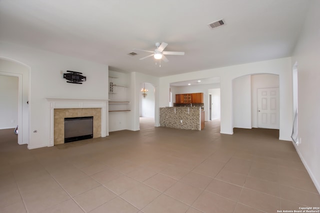 unfurnished living room featuring tile floors, ceiling fan, and a fireplace