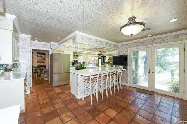 kitchen featuring white cabinets, stainless steel fridge, kitchen peninsula, and french doors