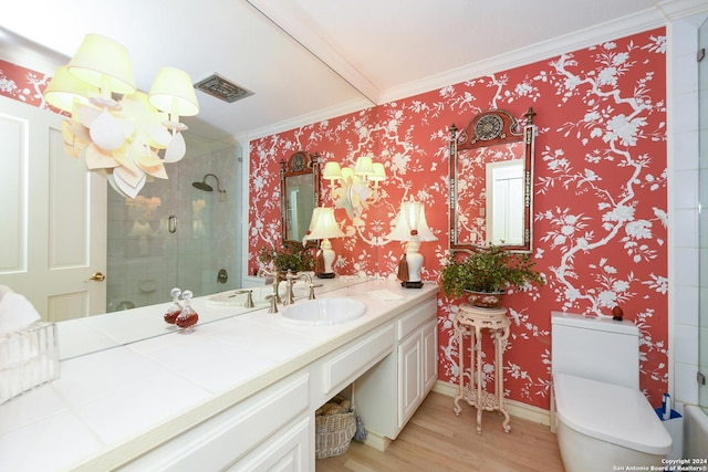 bathroom with hardwood / wood-style floors, toilet, a shower with shower door, and crown molding