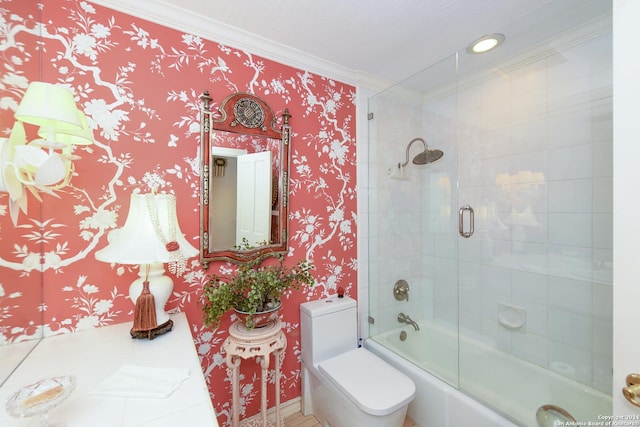 bathroom with toilet, ornamental molding, and bath / shower combo with glass door