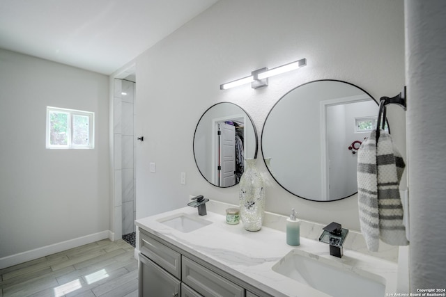 bathroom with double vanity, baseboards, a sink, and wood finished floors