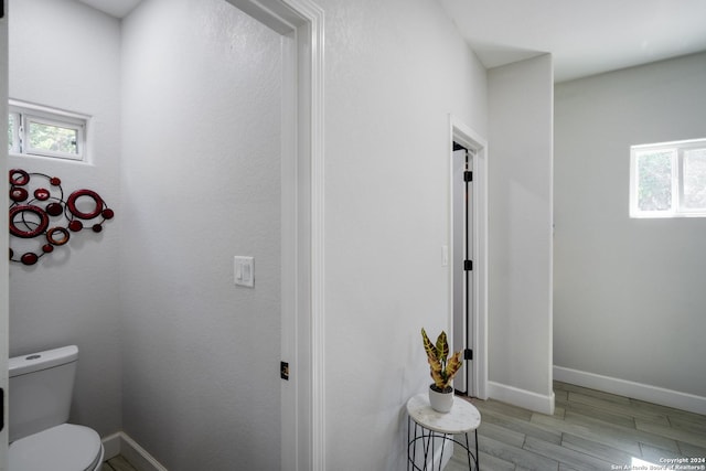 bathroom with toilet, baseboards, and wood finished floors