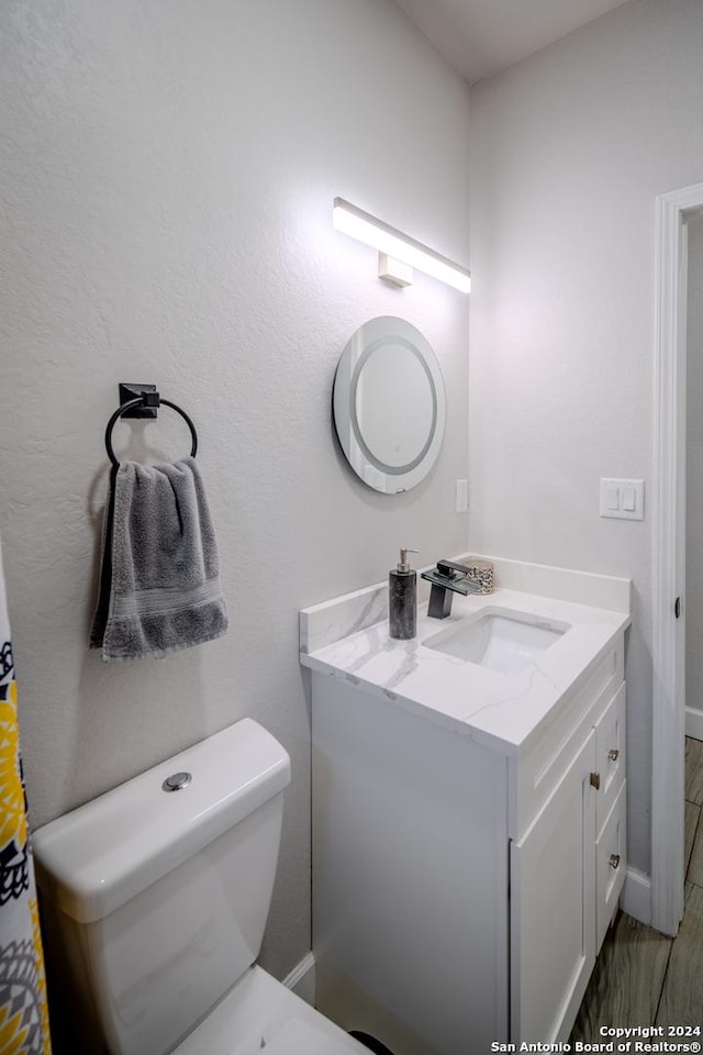 bathroom with toilet, vanity, and baseboards