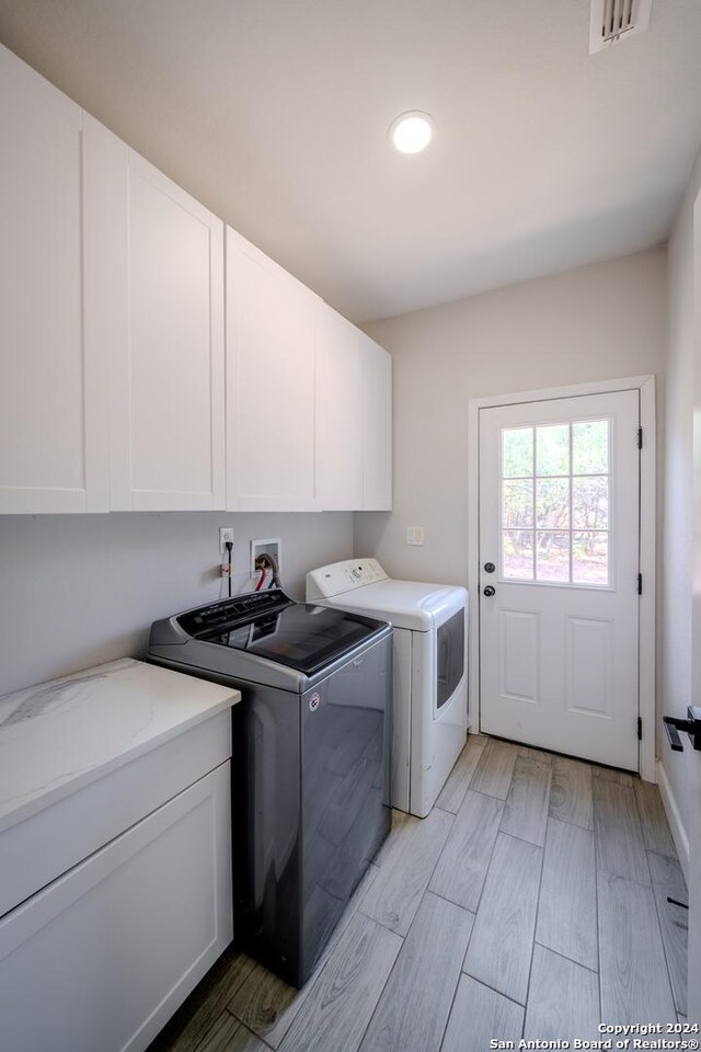 washroom featuring washer and dryer, cabinets, washer hookup, and light hardwood / wood-style floors