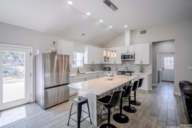 kitchen featuring stainless steel appliances, visible vents, a kitchen bar, and tasteful backsplash