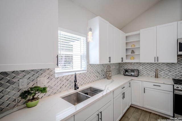 kitchen featuring light hardwood / wood-style flooring, vaulted ceiling, backsplash, sink, and white cabinetry