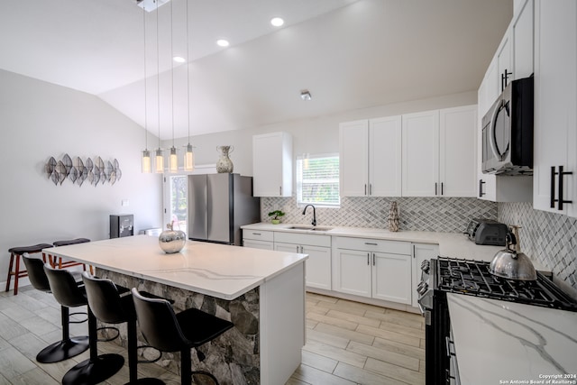 kitchen featuring a center island, stainless steel appliances, pendant lighting, sink, and vaulted ceiling