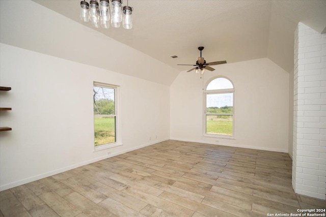 unfurnished room with lofted ceiling, ceiling fan, a healthy amount of sunlight, and light wood-type flooring