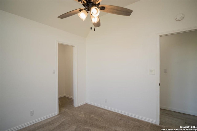 empty room with lofted ceiling, ceiling fan, and light carpet