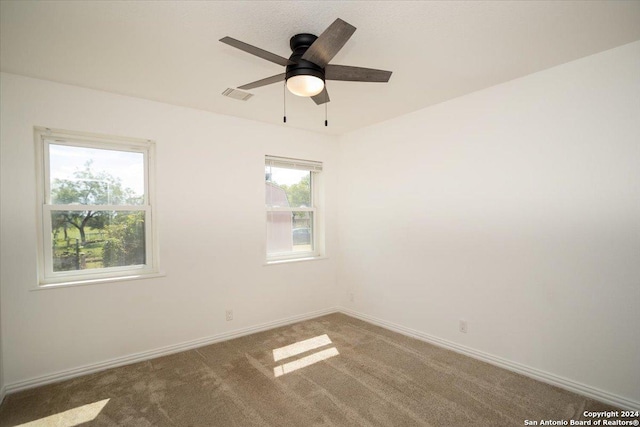 carpeted empty room with ceiling fan and plenty of natural light