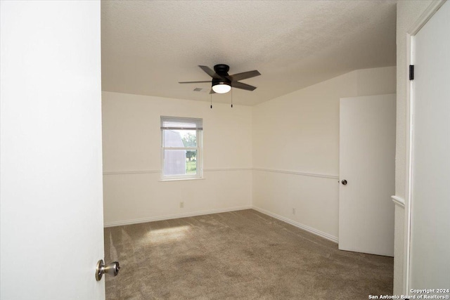 carpeted empty room with vaulted ceiling, a textured ceiling, and ceiling fan