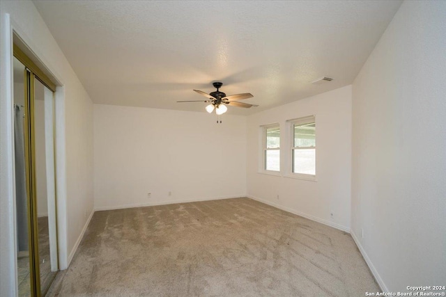 spare room with ceiling fan, light carpet, and a textured ceiling