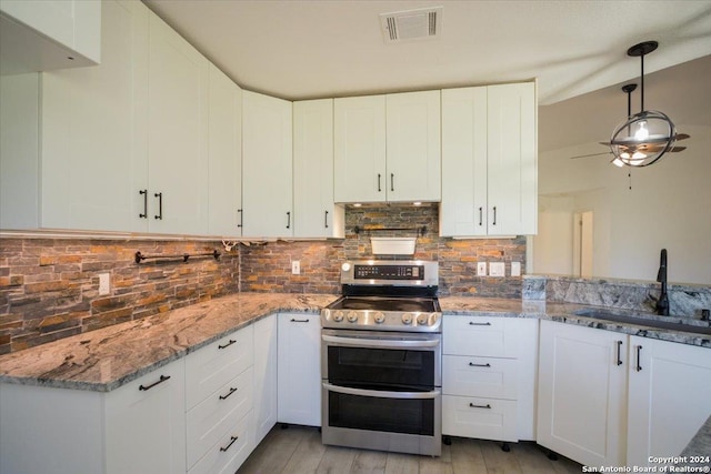 kitchen with sink, white cabinets, double oven range, and light stone countertops