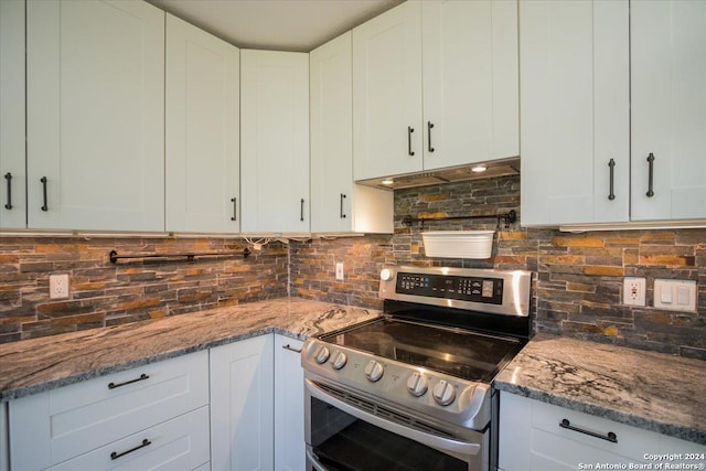 kitchen with stainless steel electric stove, white cabinetry, tasteful backsplash, and dark stone counters