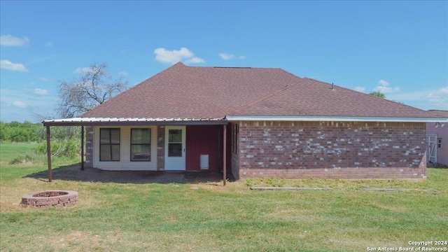 back of property featuring a lawn and a fire pit