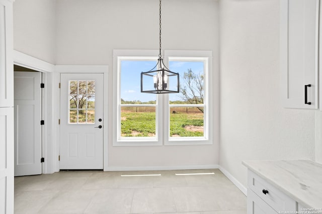 unfurnished dining area with light tile patterned flooring, a chandelier, and a healthy amount of sunlight