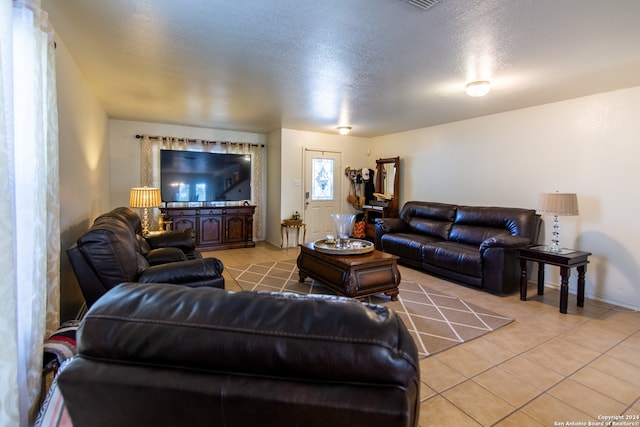 living room with a textured ceiling and light tile floors