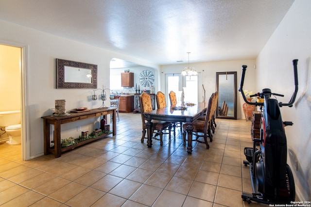 dining room featuring tile floors, a textured ceiling, and a chandelier