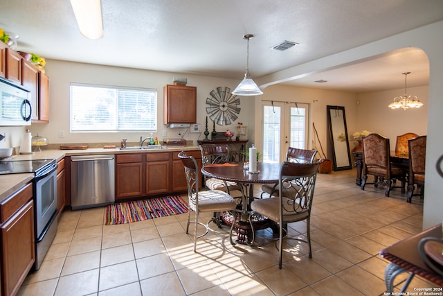 kitchen with hanging light fixtures, appliances with stainless steel finishes, a notable chandelier, sink, and light tile floors