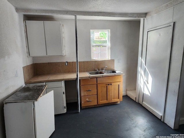 kitchen featuring sink, white cabinets, and a textured ceiling