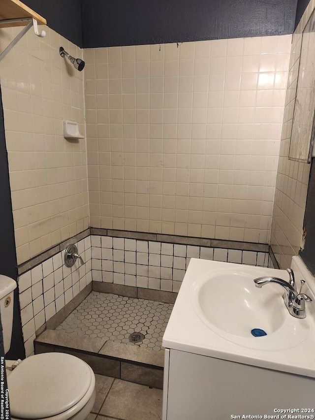 bathroom featuring a tile shower, tile patterned flooring, vanity, and toilet