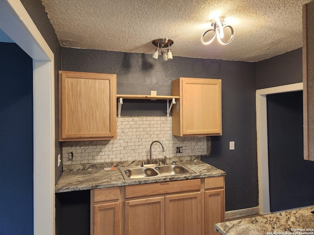 kitchen with a textured ceiling, tasteful backsplash, and sink