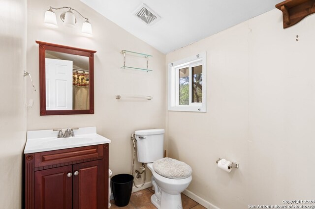 bathroom featuring tile patterned flooring, vanity, vaulted ceiling, and toilet