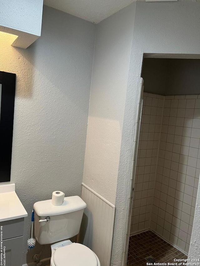 bathroom featuring tiled shower, vanity, and toilet