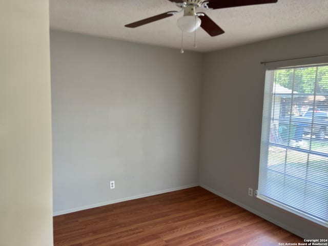 empty room featuring ceiling fan, hardwood / wood-style flooring, and a textured ceiling