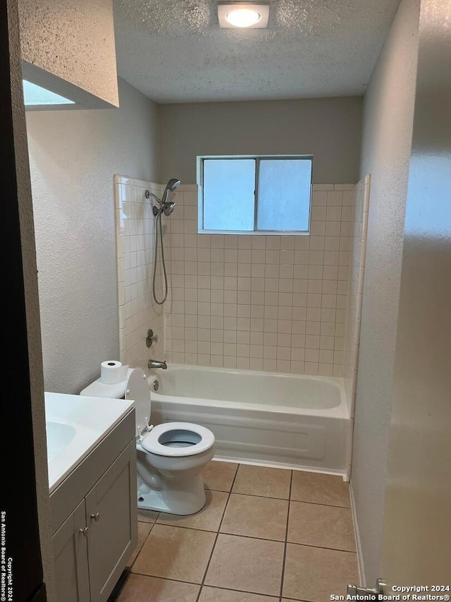 full bathroom featuring a textured ceiling, tiled shower / bath, vanity, and toilet