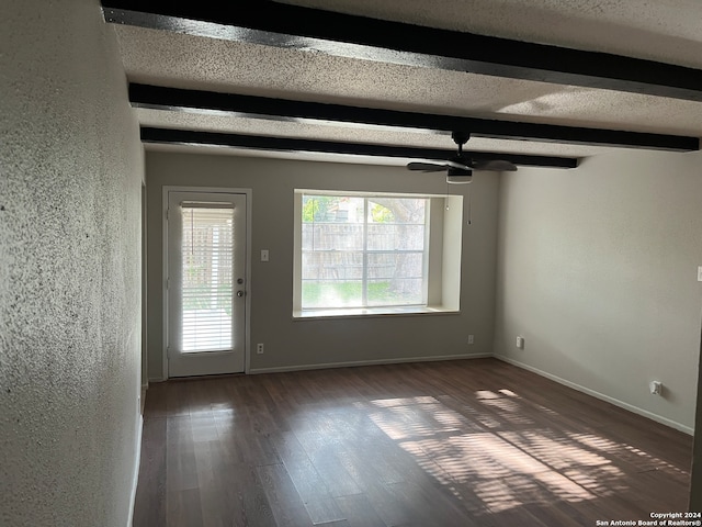 empty room with beamed ceiling, a textured ceiling, dark wood-type flooring, and ceiling fan