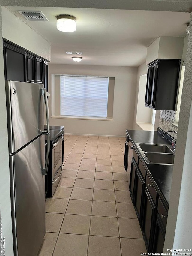 kitchen featuring backsplash, sink, stainless steel fridge, and light tile flooring