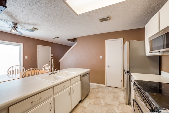 kitchen featuring stainless steel appliances, sink, a textured ceiling, light tile patterned flooring, and ceiling fan