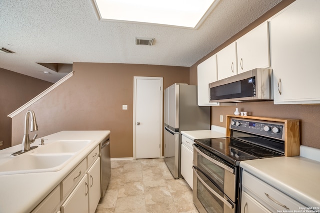 kitchen with white cabinets, sink, appliances with stainless steel finishes, a textured ceiling, and light tile patterned floors