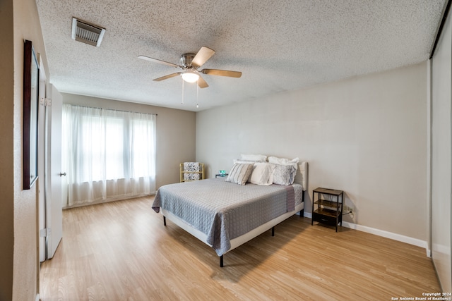 bedroom featuring ceiling fan, a textured ceiling, and light hardwood / wood-style flooring